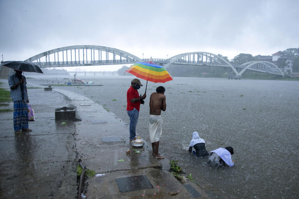 Relatives of a person who died of reasons other than COVID-19 perform rituals in Periyar river during heavy rains in Kochi, Kerala state, India, Saturday, May 15, 2021. With cyclonic storm "Tauktae" intensifying over the Arabian Sea, the southern state is receiving heavy rains amid a lockdown imposed to curb the spread of coronavirus. (AP Photo/R S Iyer)