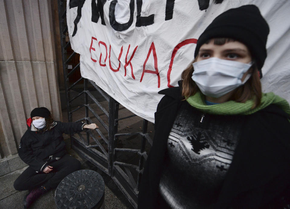 A woman is handcuffed to the gate in front of the Education Ministry building in Warsaw, Poland, on Monday Nov. 23, 2020. Police detained several people as women-led protests over abortion rights flared up again in Warsaw and elsewhere in Poland. The protests, organized by the group Women's Strike, have been occurring regularly ever since the country's constitutional court issued an Oct. 22 ruling that further tightens an abortion law that was already one of the most restrictive in Poland.(AP Photo/Czarek Sokolowski)