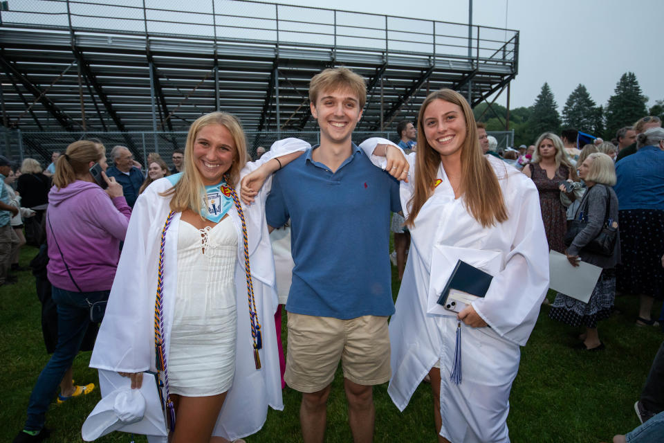 Jack Nardone poses between his twin sisters Clara and Sofia at their graduation on Friday at Winnacunnet High School.