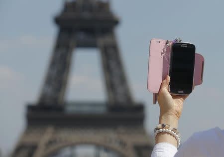 A woman uses her mobile phone to take a selfie picture at the Trocadero Square near the Eiffel Tower in Paris, May 16, 2014. REUTERS/Christian Hartmann