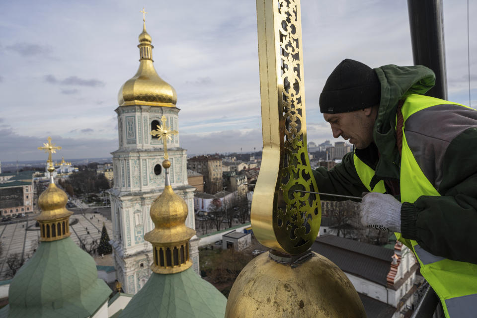 Ihor Kuzmenko, altitude worker secures a restored cross on a dome of Saint Sophia Cathedral in Kyiv, Ukraine, Thursday, Dec. 21, 2023. A UNESCO World Heritage site, the gold-domed St. Sophia Cathedral, located in the heart of Kyiv, was built in the 11th century and designed to rival the Hagia Sophia in Istanbul. The monument to Byzantine art contains the biggest collection of mosaics and frescoes from that period, and is surrounded by monastic buildings dating back to the 17th century. (AP Photo/Evgeniy Maloletka)