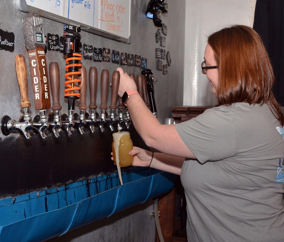 In this Feb. 1, 2019 photo, Blue Ghost bartender Emily Weber pours the first pint of a new craft beer called Re-cre8 that was brewed specifically for a fundraiser to benefit Bill Moore Community Park in Fletcher.