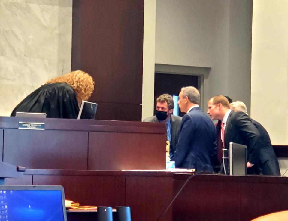 Circuit Court Judge Shonna Young Gay listens as State Attorney Larry Basford, center in blue suit jacket, Assistant State Attorney Jacob Cook, behind Basford, leaning in, and defense attorneys discuss a legal point.