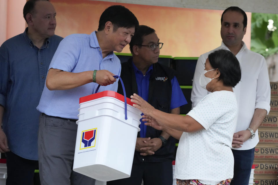 Philippine President Ferdinand Marcos Jr., second from left, hands over relief goods to an evacuee as he visits an evacuation center in Guinobatan town, Albay province, northeastern Philippines, Wednesday, June 14, 2023. A gentle eruption of the Philippines' most active volcano that has forced nearly 18,000 people to flee to emergency shelters could last for months and create a protracted crisis, officials said Wednesday. (AP Photo/Aaron Favila)