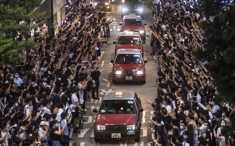 Taxis drive down a road occupied by protesters in the Causeway Bay district  - Credit: Chan Long Hei/Bloomberg