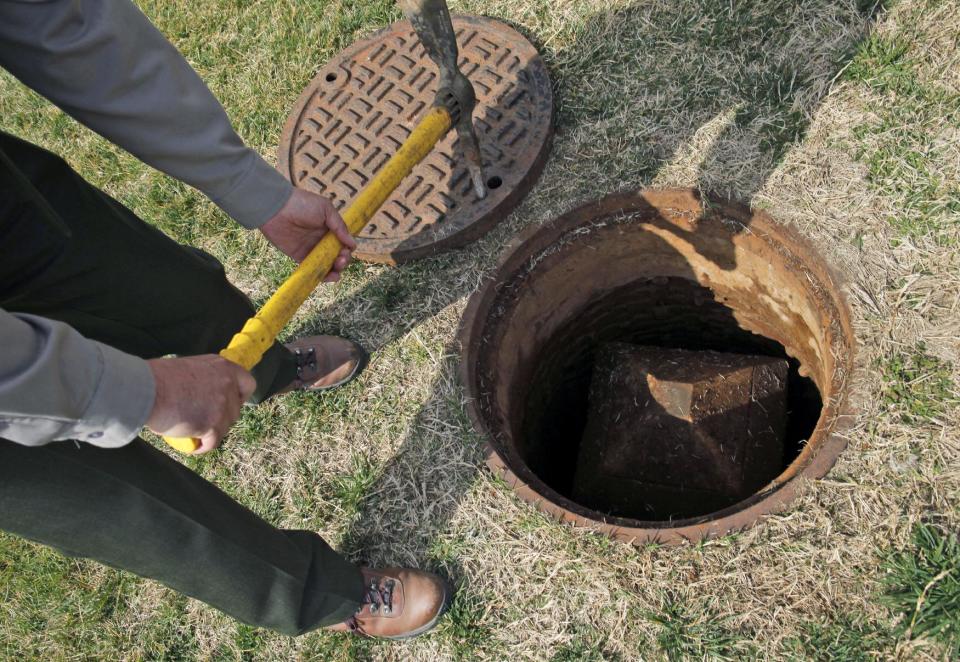 Ned Wallace of the National Park Service stands over a manhole at the base of the Washington Monument in Washington, Tuesday, March 13, 2012, containing a smaller obelisk in a well 12-feet deep which was used as a geodetic marker and referred to as "the mini monument". Government surveyors are collecting data around the Washington Monument and other sites on the National Mall that will reveal whether it has sunk or tilted since last yearís earthquake. (AP Photo/Charles Dharapak)