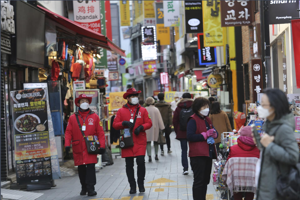 Tourist information helpers wearing face masks walk along a popular shopping street in Seoul, South Korea, Wednesday, Dec. 2, 2020. (AP Photo/Ahn Young-joon)