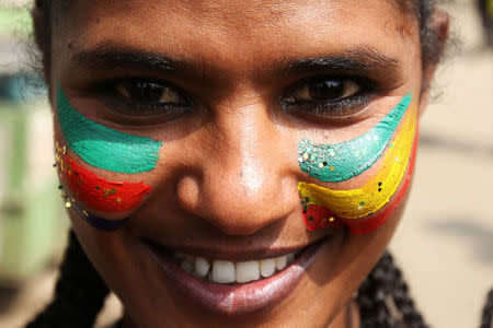 A woman with a face painting of the Ethiopia national flag attends a ceremony to welcome Eritrea's President Isaias Afwerki for a three-day visit, at the Bole international airport in Addis Ababa, Ethiopia July 14, 2018. REUTERS/Tiksa Negeri