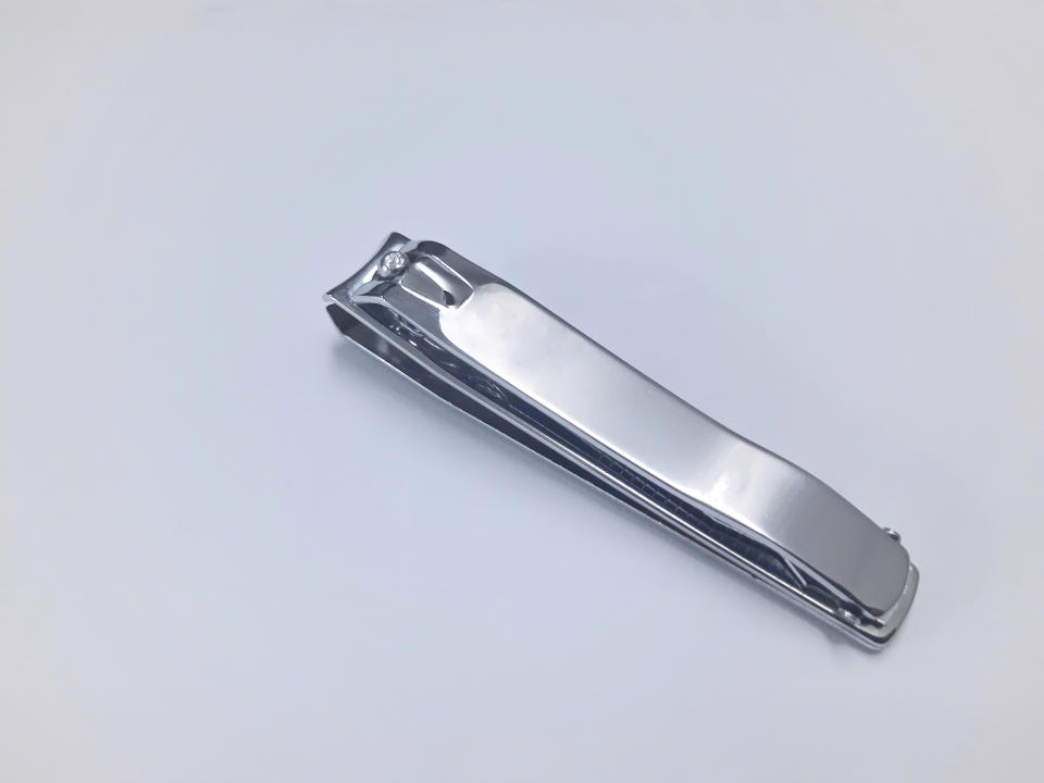 A metallic nail clipper resting on a plain surface