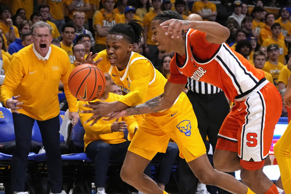 Pittsburgh's Carlton Carrington, center, and Syracuse's Judah Mintz, right, vie for the ball during the first half of an NCAA college basketball game in Pittsburgh on Tuesday, Jan. 16, 2024. (AP Photo/Gene J. Puskar)