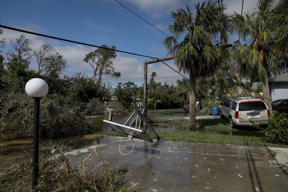 A broken utility pole behind a collapsed basketball hoop on a flooded street following Hurricane Ian in Fort Myers, Fla., on Sept. 29.<span class="copyright">Eva Marie Uzcategui—Bloomberg/Getty Images</span>