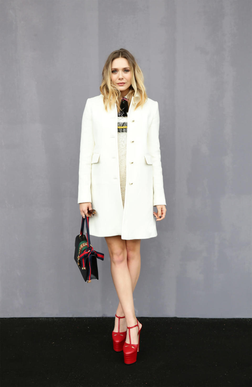 Elizabeth Olsen attends the Gucci Fall/Winter 2016 show in Milan wearing a mod-style white coat and collared dress.