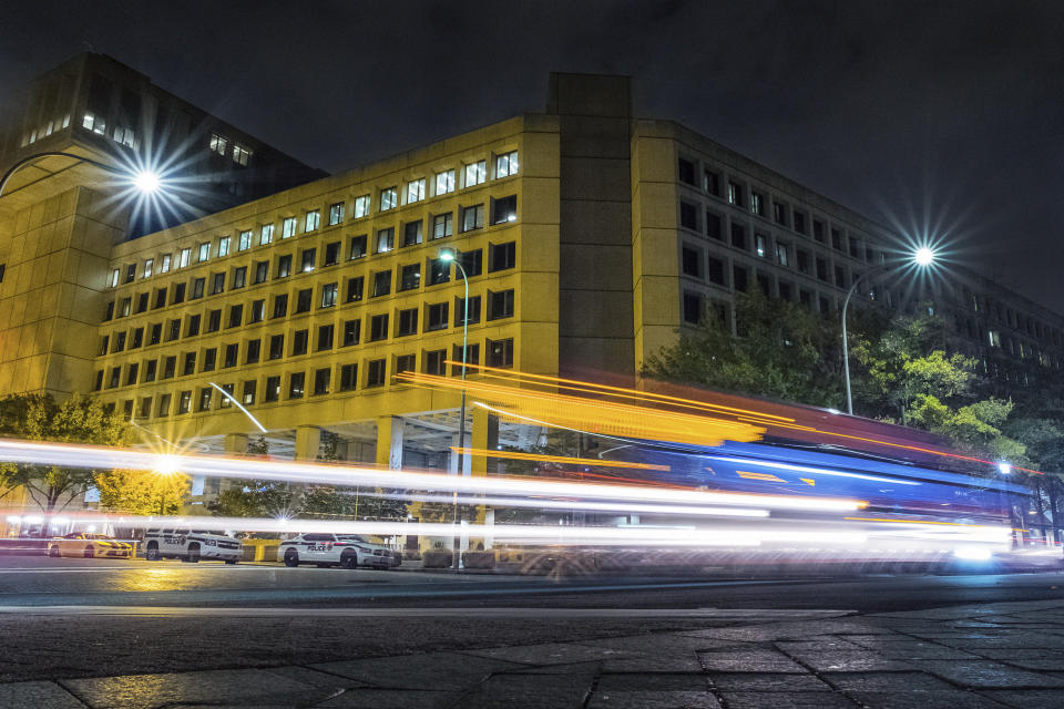 FILE - In this Nov. 1, 2017, file photo, traffic along Pennsylvania Avenue in Washington streaks past the Federal Bureau of Investigation headquarters building. In an alert Wednesday, Oct. 28, 2020, the FBI and other federal agencies warned that cybercriminals are unleashing a wave of data-scrambling extortion attempts against the U.S. healthcare system that could lock up their information systems just as nationwide cases of COVID-19 are spiking. (AP Photo/J. David Ake, File)