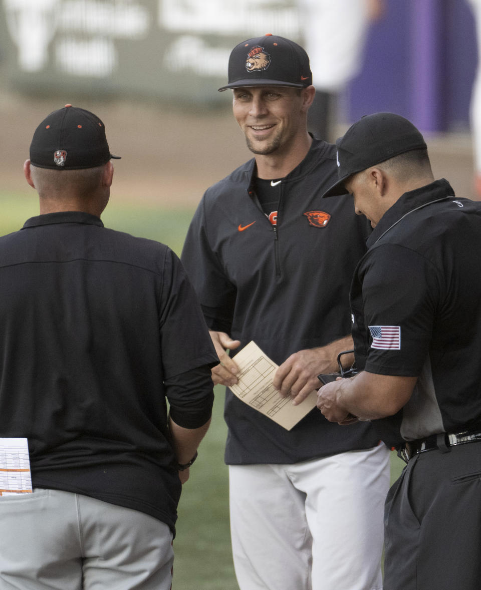 Oregon State head coach Mitch Canham, center, meets with officials before the first pitch against Sam Houston State in an NCAA college baseball tournament regional game Friday, June 2, 2023, in Baton Rouge, La. (Hilary Scheinuk/The Advocate via AP)