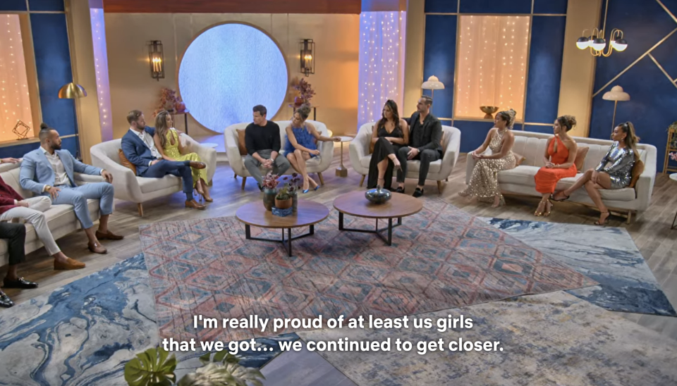 The cast seated in a semicircle, with the caption "I'm really proud of at least us girls that we got...we continued to get closer"