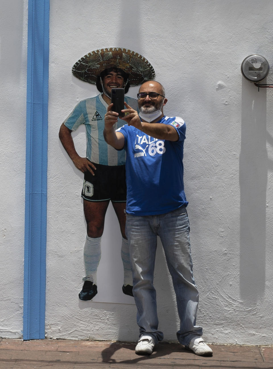 A tourist takes a selfie in front of the Church of Maradona in San Andres Cholula, Puebla state, Mexico, Sunday, July 18, 2021. The Church of Maradona in Mexico, dedicated to late soccer great Diego Armando Maradona, was founded a few weeks ago by Argentine expatriate Buchet, who also owns the pizza parlor next door. (AP Photo/Marco Ugarte)