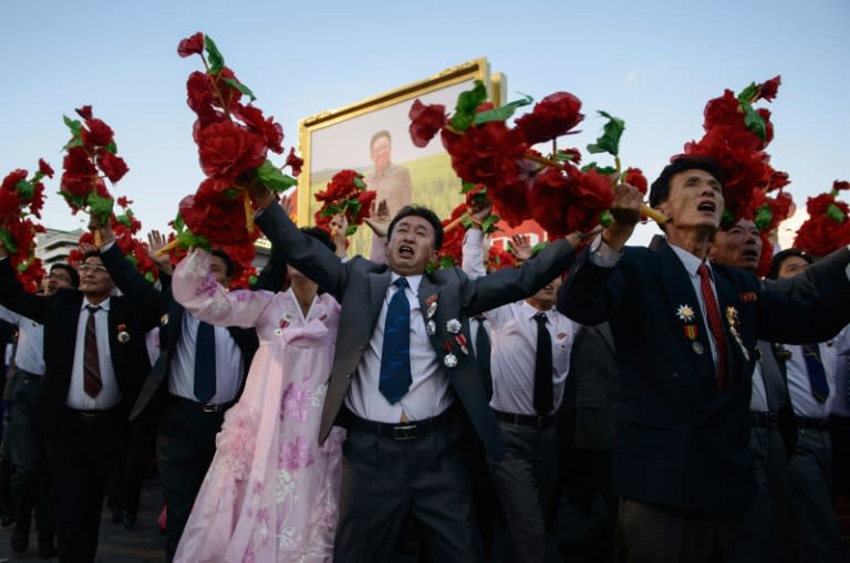 Participants wave flowers at North Korean leader Kim Jong-Un as they pass through Kim Il-Sung square during a mass military parade in Pyongyang in October 2015