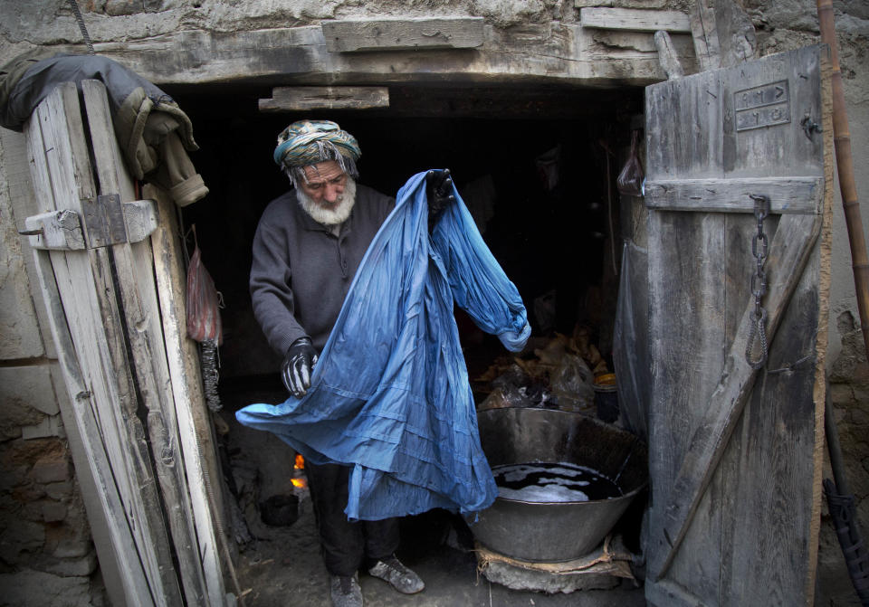 Haji Hussain, 75, who colors clothing for 40 years, takes a freshly colored burqa out for drying in his small shop in the old town of Kabul, Afghanistan, Monday, April 15, 2013. Despite advances in women’s rights, Afghanistan remains a deeply conservative country and most women continue to wear the Burqa. But tradesmen say times are changing in Kabul at least, with demand for burqas declining as young women going to school and taking office jobs refuse to wear the cumbersome garments. (AP Photo/Anja Niedringhaus)