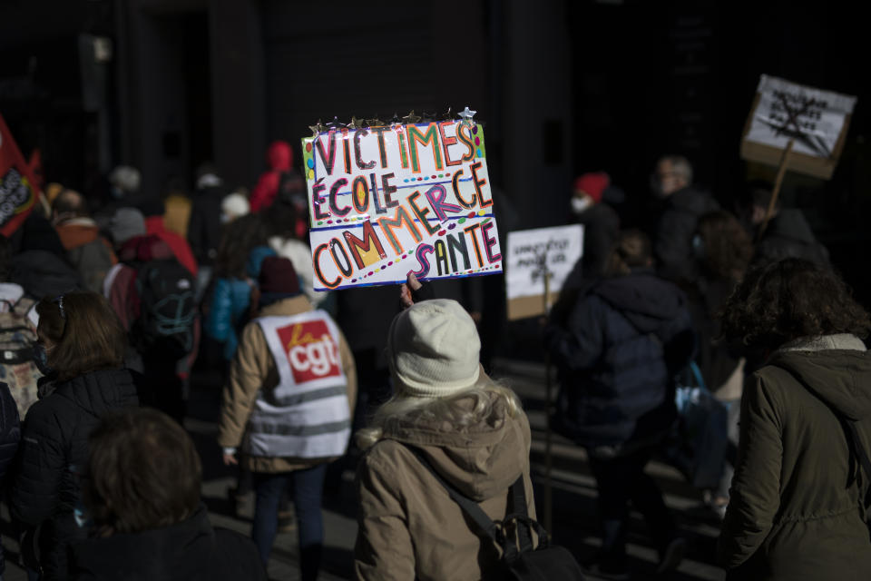 A protester holds a sign that reads "victims: school, business, healthcare" during a demonstration in Marseille, southern France, Tuesday Jan. 26, 2021. Teachers and university students marched together in protests or went on strike Tuesday around France to demand more government support amid the pandemic. (AP Photo/Daniel Cole)