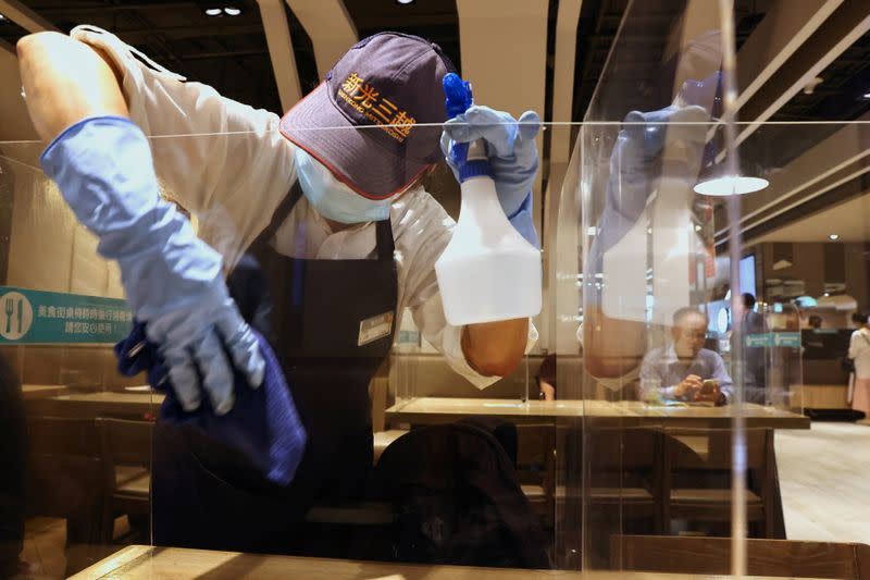 A staff member cleans the plastic partitions at a canteen following the outbreak of coronavirus disease (COVID-19), in Taipei