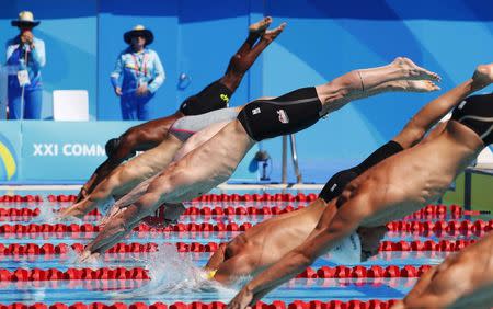 Swimming - Gold Coast 2018 Commonwealth Games - Men's 50m Freestyle - Heats - Optus Aquatic Centre - Gold Coast, Australia - April 9, 2018. Benjamin Proud (in red cap) of England dives into the water with fellow competitors during heat 8 of the men's 50m freestyle competition. REUTERS/David Gray