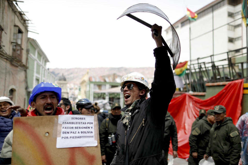 Opponents of former Bolivian President Evo Morales hold shields at a barricade set up by protesters outside presidential palace in La Paz, Bolivia, Monday, Nov. 11, 2019. Morales' Nov. 10 resignation, under mounting pressure from the military and the public after his re-election victory triggered weeks of fraud allegations and deadly demonstrations, leaves a power vacuum and a country torn by protests against and for his government. (AP Photo/Natacha Pisarenko)