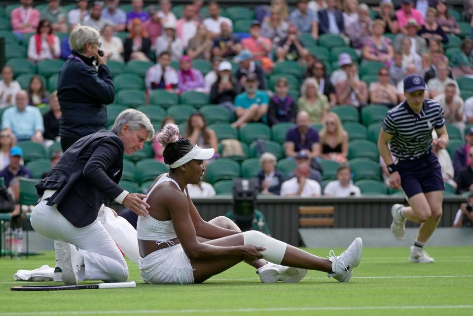 Officials assist after Venus Williams of the US slipped as she plays Ukraine's Elina Svitolina, left, in a first round women's singles match on day one of the Wimbledon tennis championships in London, Monday, July 3, 2023. (AP Photo/Kin Cheung)