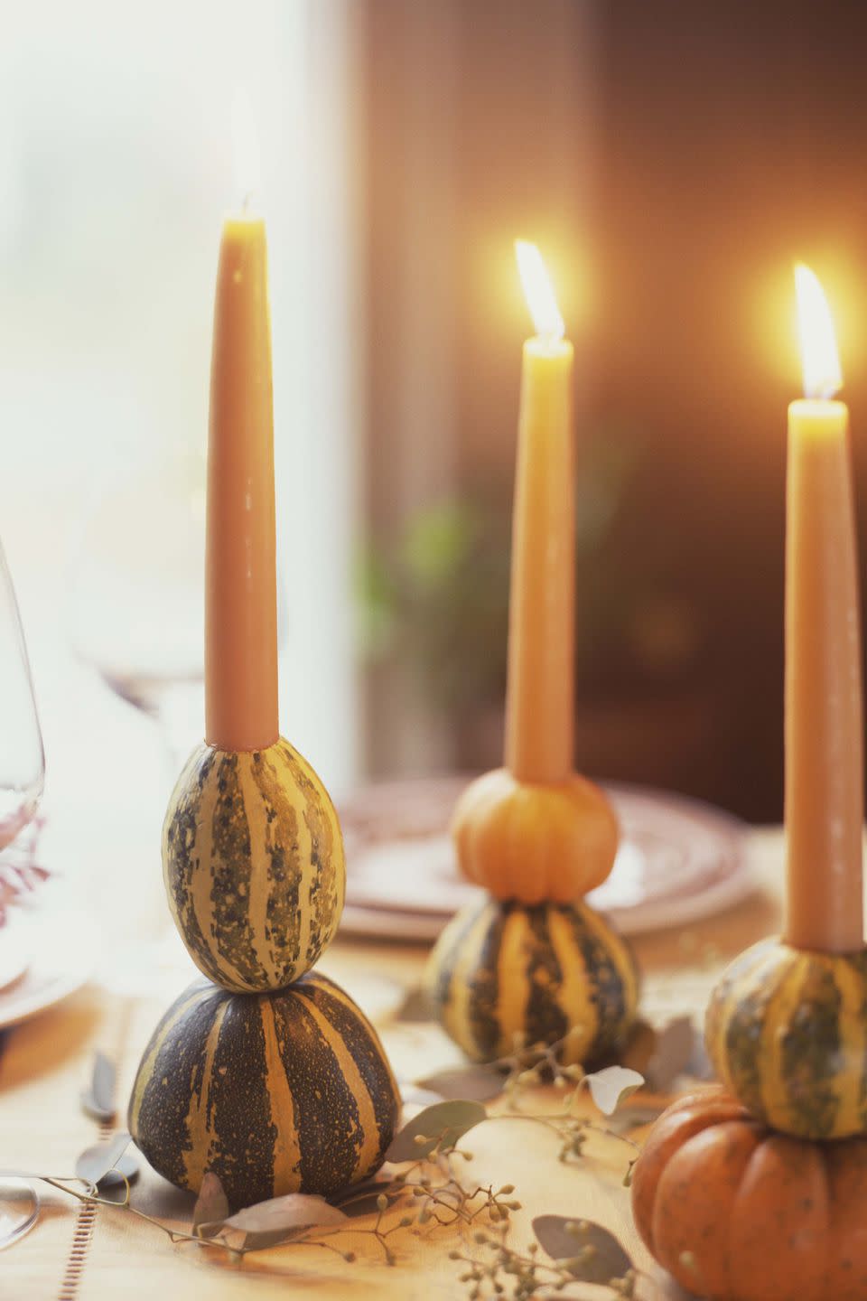 <p>Use a drill to hollow out the center of two gourds or mini pumpkins, then stack atop one another and insert a taper candle for a festive Thanksgiving candlestick. </p>