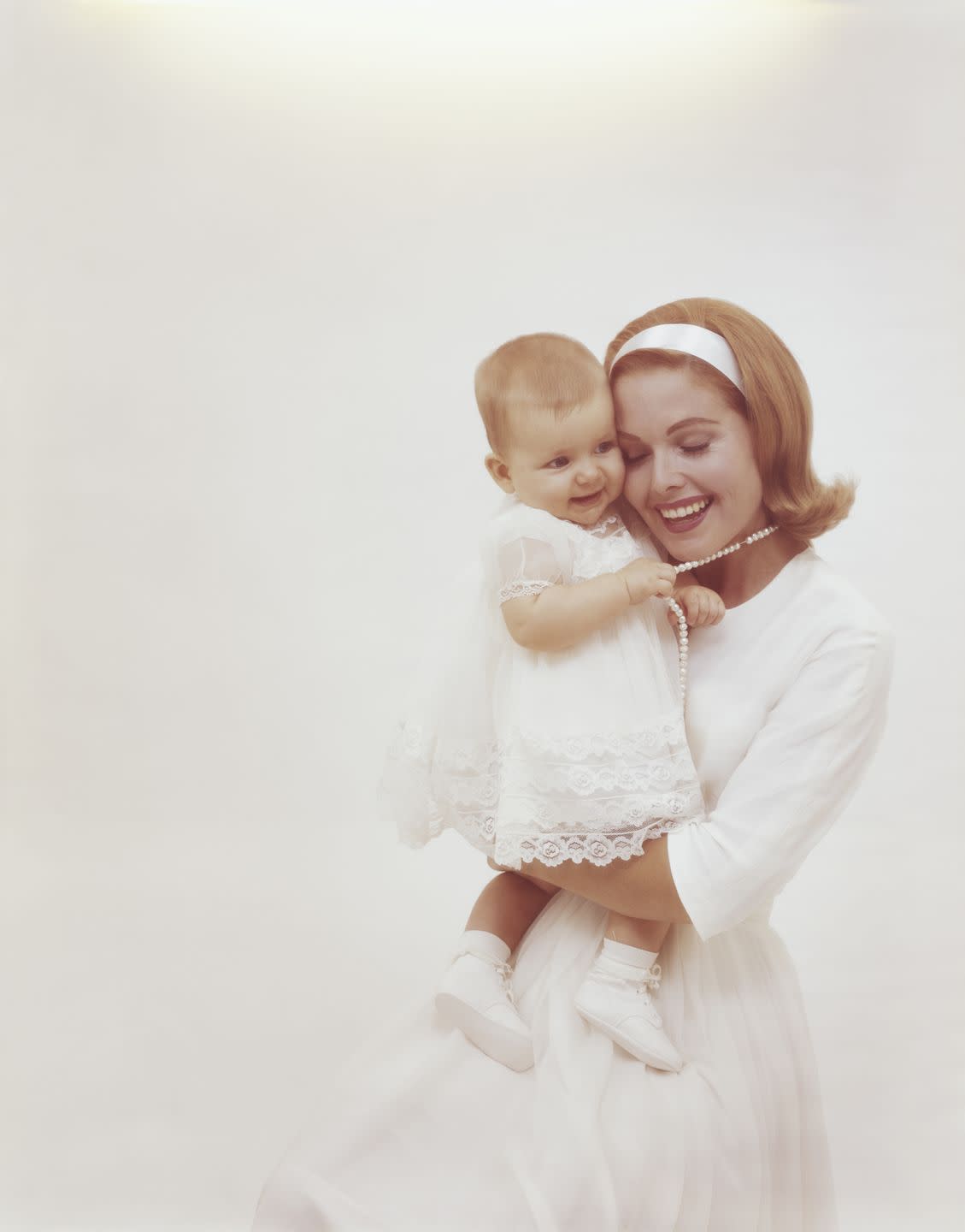 mother carrying baby girl against white background