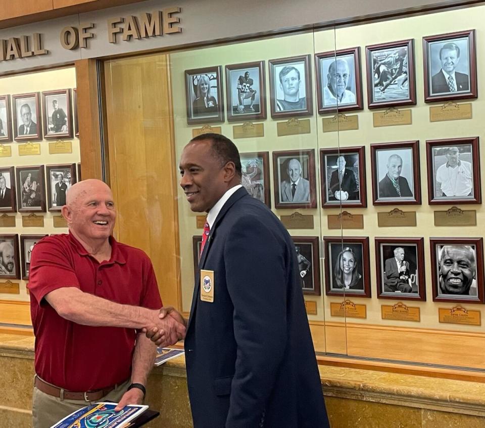 Jeff Webb, left, shakes hands with past ASA president Bernard Johnson in front of the ASA HOF plaques at the Emerald Coast Convention Center.