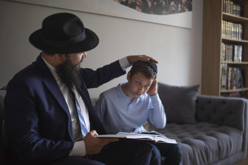 Chabad-Lubavitch Rabbi Levi Banon and his son Mendel, 12, read a religious text at their home library in Casablanca, Morocco, Thursday, May 28, 2020. (AP Photo/Mosa'ab Elshamy)