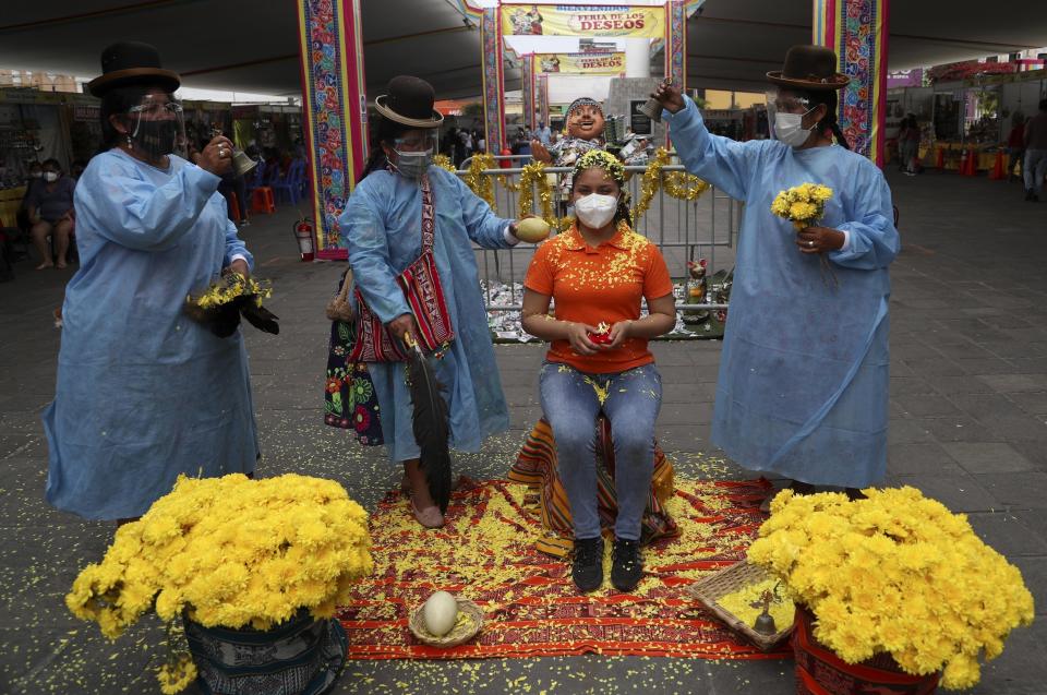 Brigite Garcés se queda quieta mientras una chamana realiza un ritual de limpieza por alrededor de 10 dólares en el "Mercado de Deseos", que se instala durante una semana en Lima, Perú, el lunes 28 de diciembre de 2020. En medio de la pandemia de COVID-19 de este año, la gente desea tener buena salud y trabajo en 2021, ya que muchos se han quedado sin ninguno de ellos. Garcés dijo que desea tener buena salud primero, trabajar en segundo lugar y luego amar. (AP Foto/Martin Mejia)