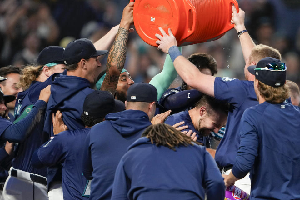 Seattle Mariners' Cal Raleigh is mobbed by teammates at home plate after hitting a game-winning grand slam for an 8-4 win over the Chicago White Sox in a baseball game, Monday, June 10, 2024, in Seattle. (AP Photo/Lindsey Wasson)