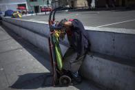 FILE - In this March 19, 2020 file photo, a porter nods off over his dolly at a street market in Lima, Peru, the fourth day of a state of emergency decreed by the government due to the new coronavirus outbreak. Many of the wealthy are already recovering from coronavirus and experts are warning that the virus could kill untold numbers in the poorest sectors of society, where not working means not eating, people live packed together and few have access to healthcare, let alone sophisticated medical care. (AP Photo/Rodrigo Abd, File)