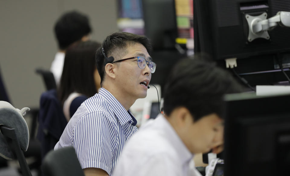 A currency trader talks on the phone at the foreign exchange dealing room in Seoul, South Korea, Tuesday, Aug. 6, 2019. Asian stocks followed Wall Street lower on Tuesday after China let its currency sink and halted purchases of U.S. farm goods, fueling fears Beijing's trade war with President Donald Trump will harm the global economy. (AP Photo/Lee Jin-man)