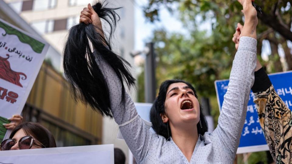 Mujer iraní tras cortarse su cabello durantes protestas en Corea del Sur.