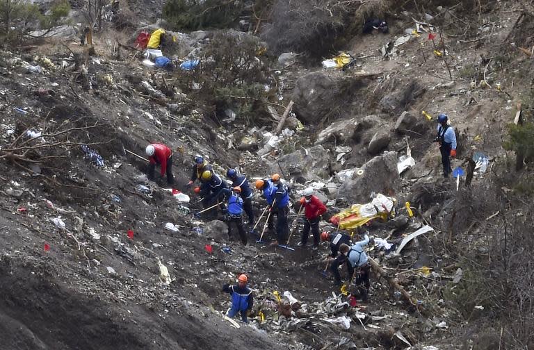 French investigators work through the scattered debris on the Germanwings crash site in the French Alps, on March 26, 2015