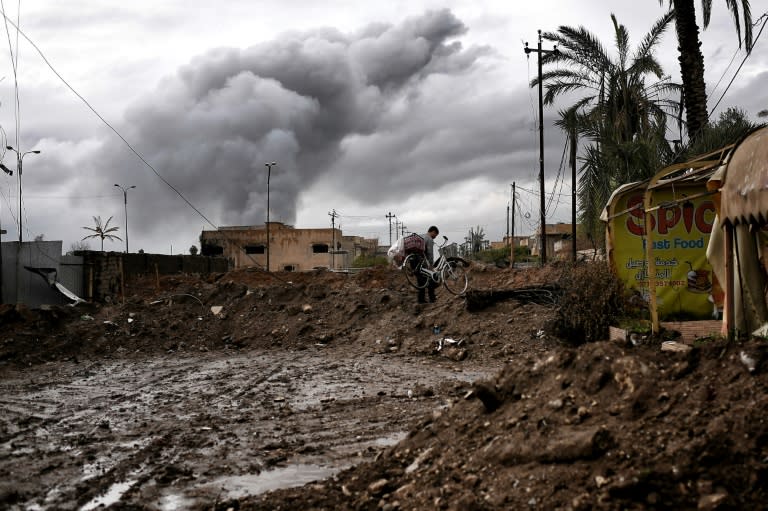 An Iraqi carries a bicycle in West Mosul during the offensive to retake the city from Islamic State group, on March 16, 2017