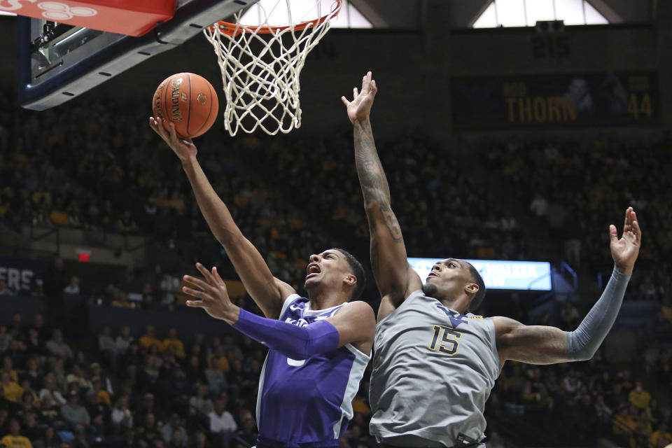 Kansas State forward David N'Guessan, left, shoots as West Virginia forward Jimmy Bell Jr. (15) defends during the first half of an NCAA college basketball game on Saturday, March 4, 2023, in Morgantown, W.Va. (AP Photo/Kathleen Batten)