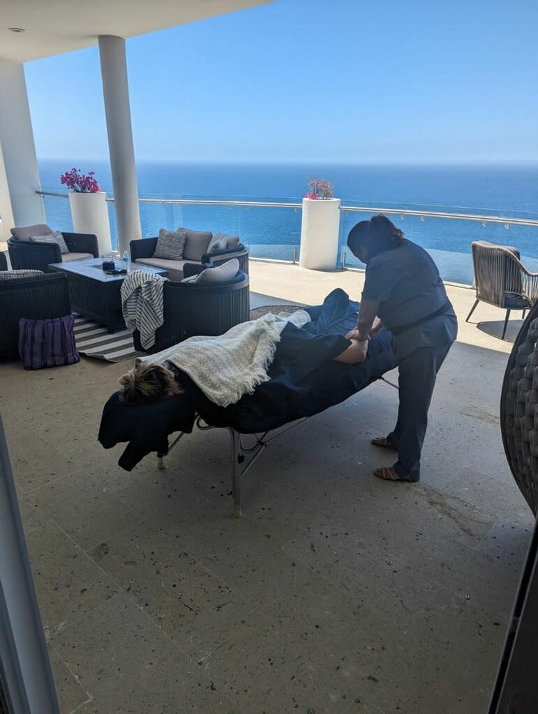 A person enjoys an outdoor massage on a terrace overlooking the sea
