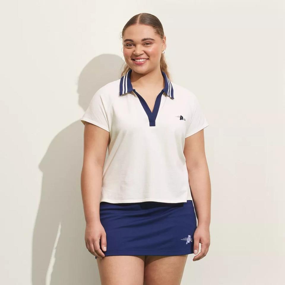 model wearing navy and cream polo shirt with navy blue tennis skirt