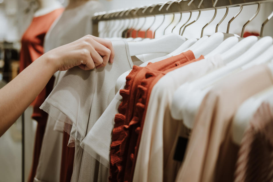 A woman inspecting clothes on a retailer rack.