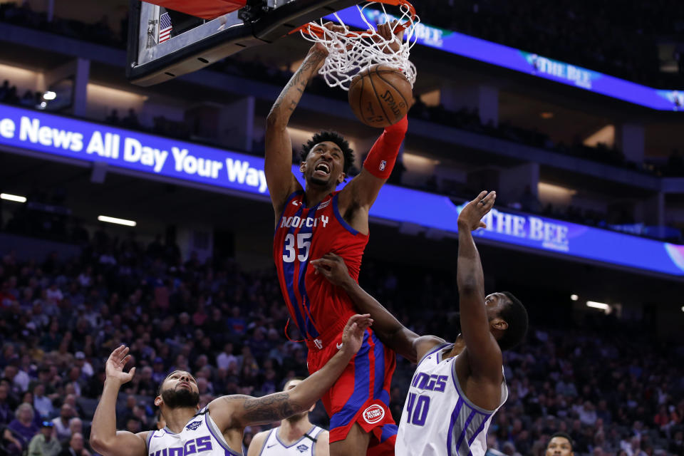 Detroit Pistons forward Christian Wood, center, stuffs over Sacramento Kings' Cory Joseph, left, and Harrison Barnes, right, during the first half of an NBA basketball game in Sacramento, Calif., Sunday, March 1, 2020. (AP Photo/Rich Pedroncelli)