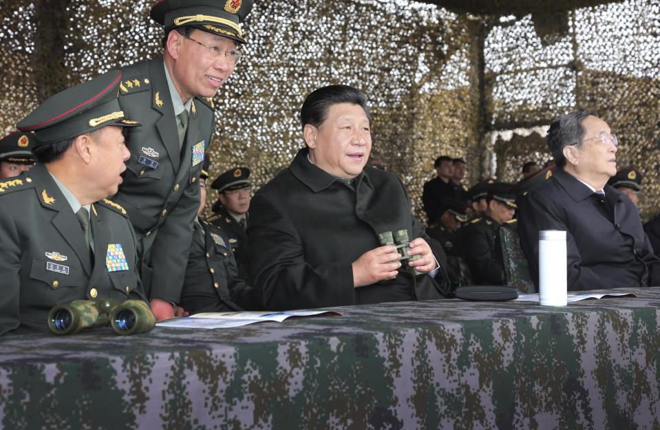 In this photo provided by China's official Xinhua News Agency, Chinese President Xi Jinping, center, watches drills of troops of the Chinese People's Liberation Army in northwest China's Xinjiang Uighur Autonomous Region Thursday, May 1, 2014. Chinese President Xi demanded "decisive" action against terrorism after the Wednesday's terror attack at a train station, which came at awkward time for him, just as he was wrapping up a four-day tour of Xinjiang aimed at underlining the government's commitment to security in the region. (AP Photo/Xinhua, Li Gang) NO SALES