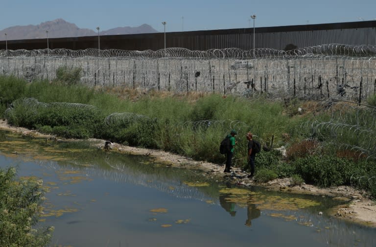 Dos migrantes al borde del muro fronterizo entre México y Estados Unidos, cerca de Ciudad Juárez, Chihuahua, México, el 5 de junio de 2024. (Herika Martinez)