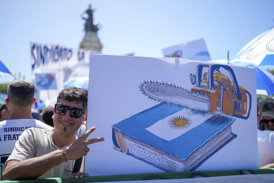 A demonstrator holds a poster showing a chainsaw over the Constitution during a march to Congress as part of a national strike to protest the economic and labor reforms proposed by Argentine President Javier Milei in Buenos Aires, Argentina, Wednesday, Jan. 24, 2024. (AP Photo/Natacha Pisarenko)