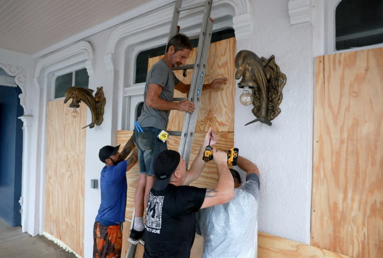 Unos trabajadores colocan unos paneles de madera en un negocio de Cedar Key, en Florida (EEUU), el 4 de agosto de 2024, ante la posible llegada de la tormenta Debby (Joe Raedle)
