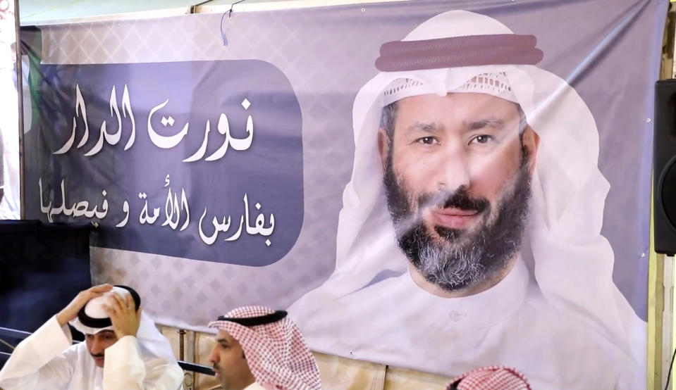 In this frame grab from video, a poster bearing the image of pardoned Islamist lawmaker Faisal al-Muslim is displayed at a celebration marking his return to Kuwait, in Kuwait City, Kuwait, Tuesday, Nov. 30, 2021. Several prominent Kuwaiti opposition figures have returned home from a decade of self-exile after getting amnesty from the ruling emir, a long-awaited move celebrated Tuesday that's aimed at ending the political paralysis that has burned a hole in public finances. (AP Photo)