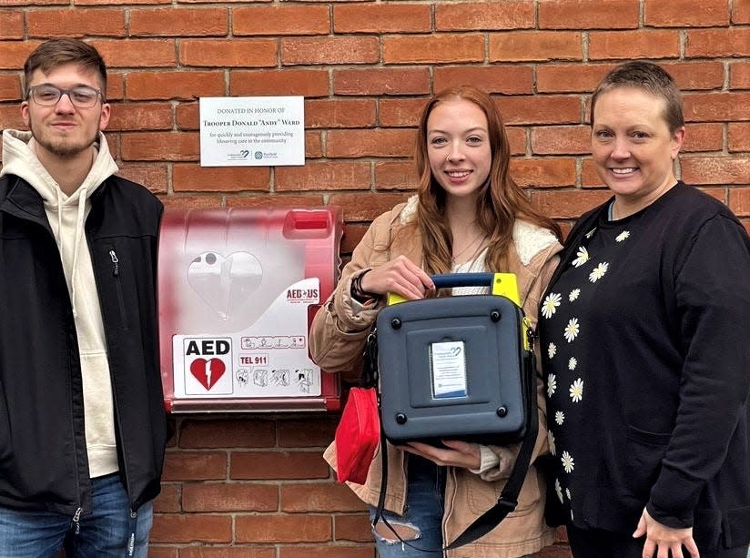 Drew, Megan and Brenda Ward stand with a newly-installed automated external defibrillator at Lancaster High School's Fulton Field April 18. The unit is dedicated to Brenda's husband, Drew and Megan's father, Ohio Highway Patrol Trooper Donald "Andy" Ward.