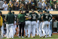 Oakland Athletics teammates help Elvis Andrus, center, off the field after he collapsed with an injury after scoring a walk-off win against the Houston Astros in the ninth inning of a baseball game in Oakland, Calif., Saturday, Sept. 25, 2021. The Athletics won 2-1. (AP Photo/John Hefti)